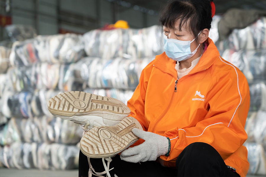 female sorter inspects the soles of a used shoe pair 3